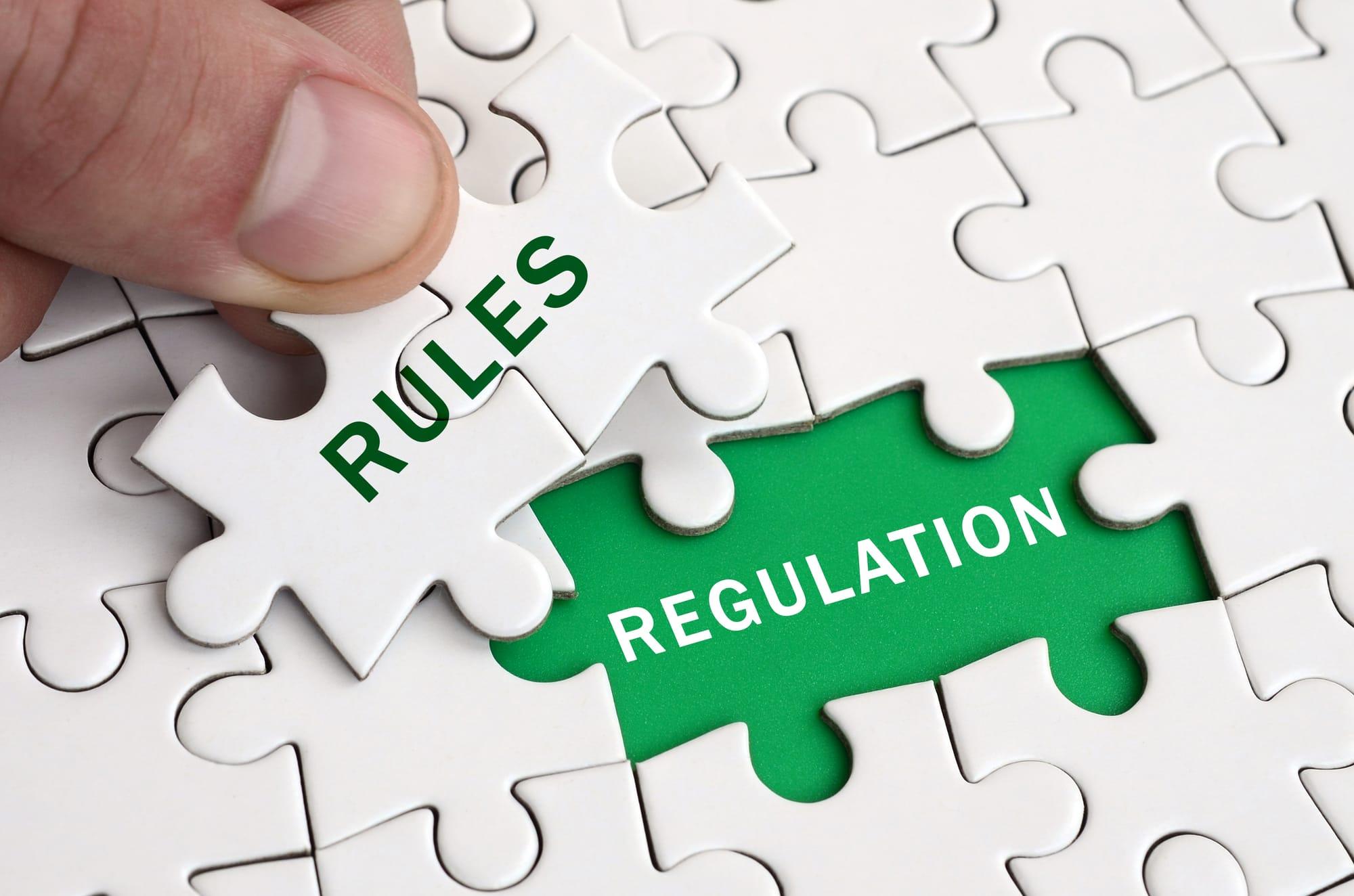 A hand placing a puzzle piece labeled "Rules" into a slot labeled "Regulation."